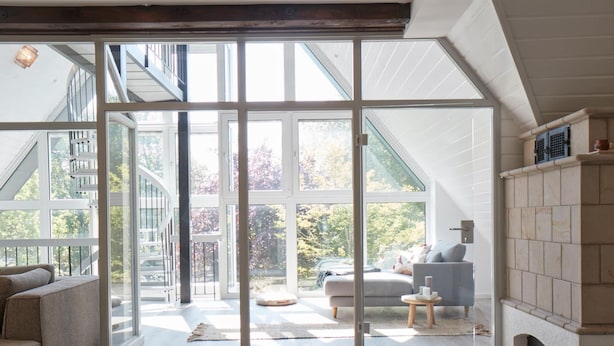 Un salon spacieux doté d’une grande porte-fenêtre coulissante donnant sur un balcon, d’une cheminée et offrant une vue sur l’extérieur.