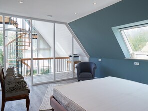 Ein Schlafzimmer mit Bett, Stuhl, Schreibtisch und einem großen Fenster.