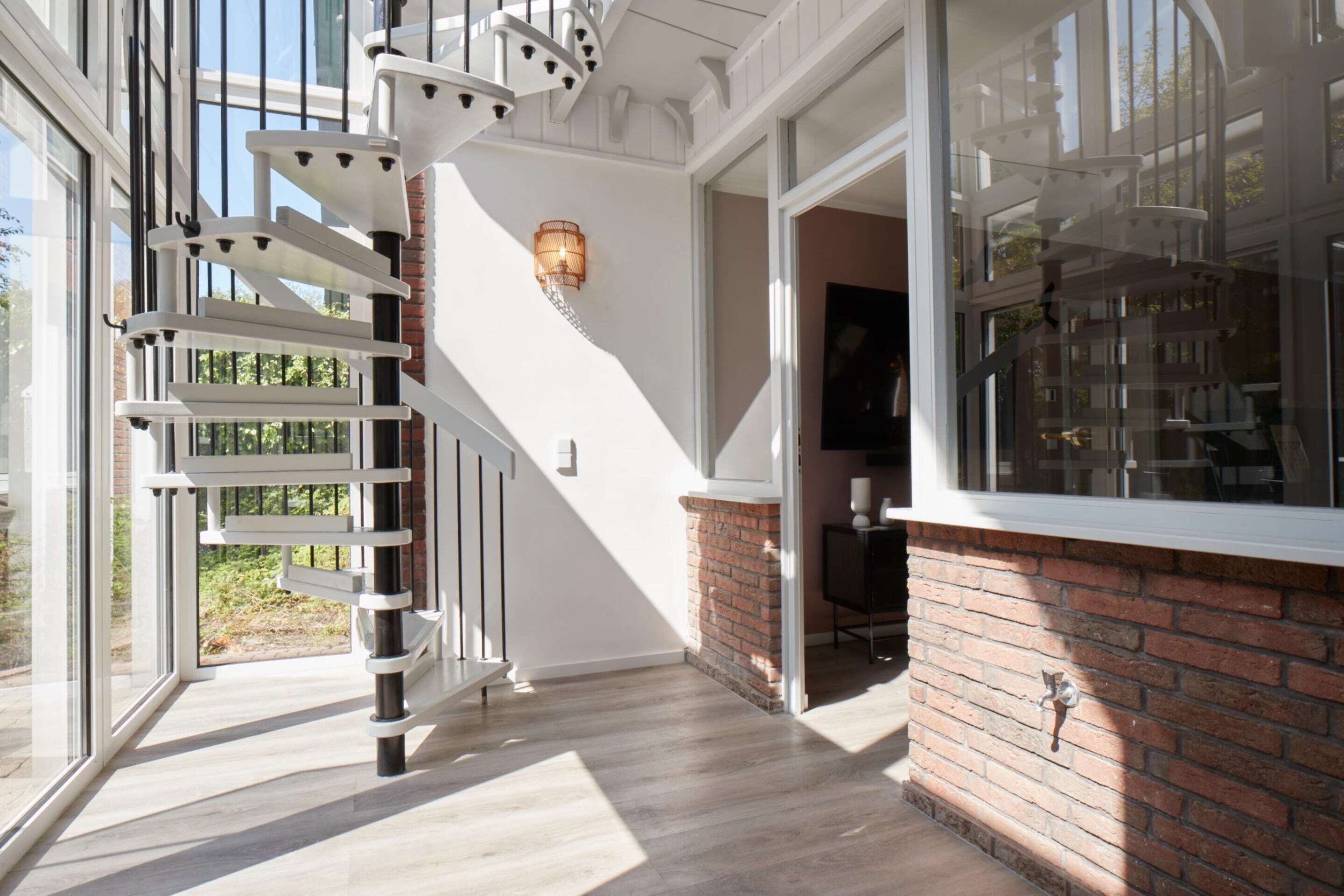 A spiral staircase with white railings and a brick wall.