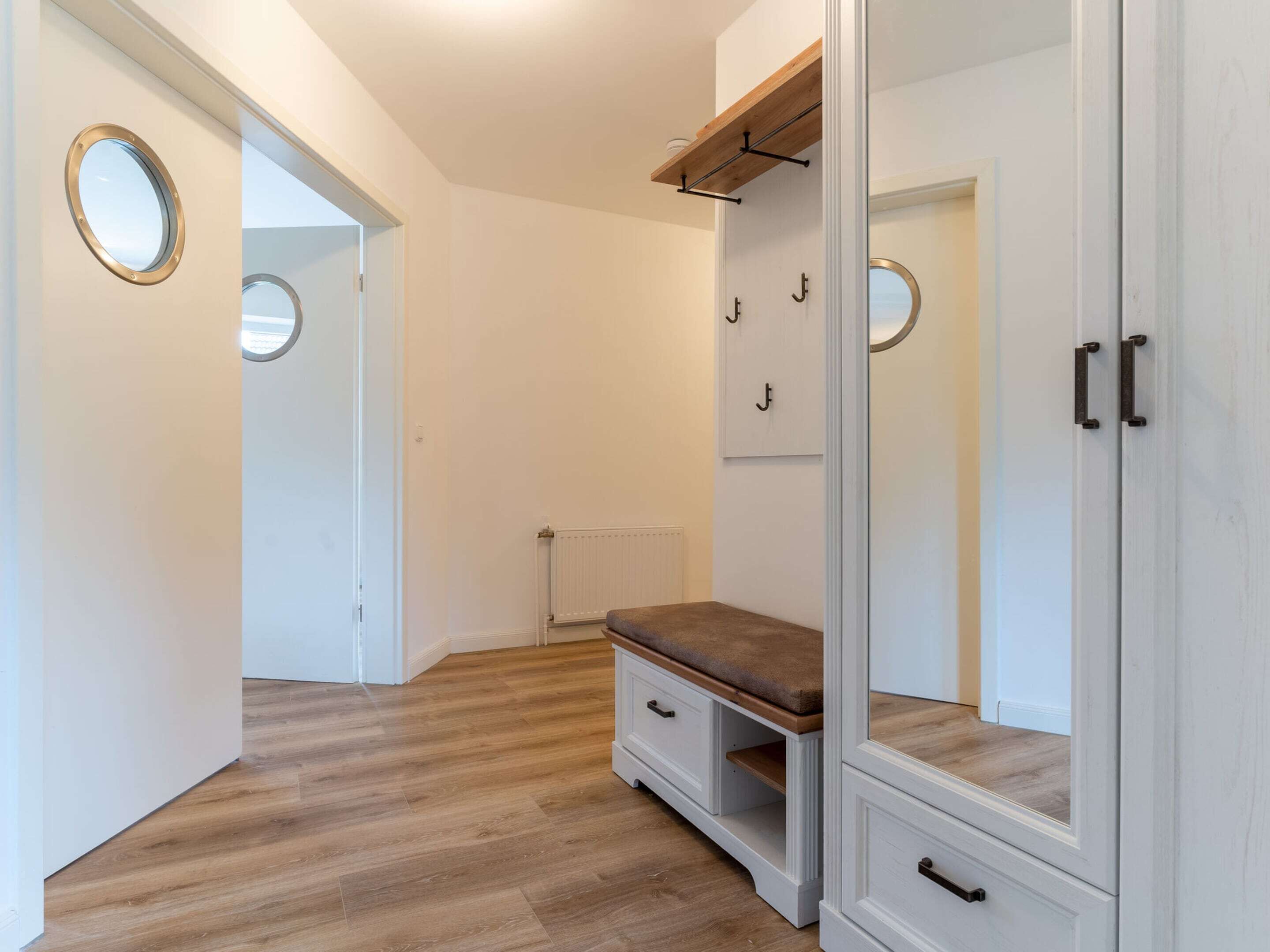 A walk-in closet with a bench, mirrored doors, and a radiator.