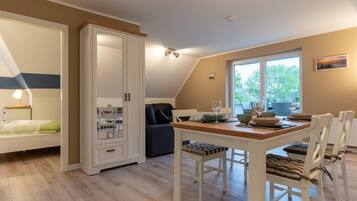Una habitación con una mesa de comedor preparada para cuatro personas, un sofá, un armario y una cama con una mesita de noche.