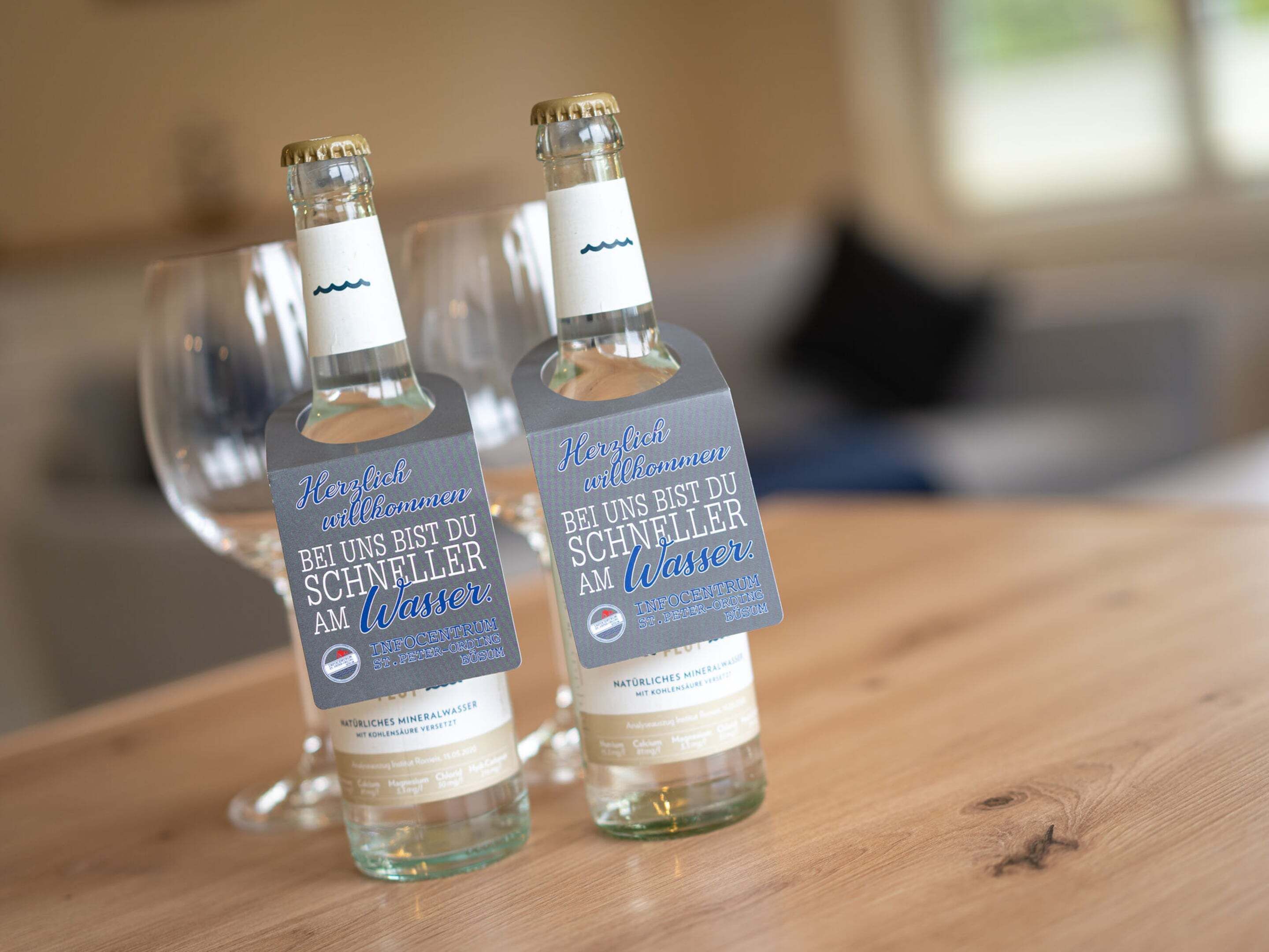 Two bottles of mineral water with labels on a wooden surface.