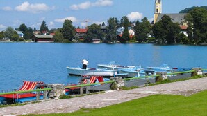 A lakeside view with boats docked, a church, and houses in the background. - Lush Apartment in Bayrischzell With 2 Saunas (Bayrischzell)