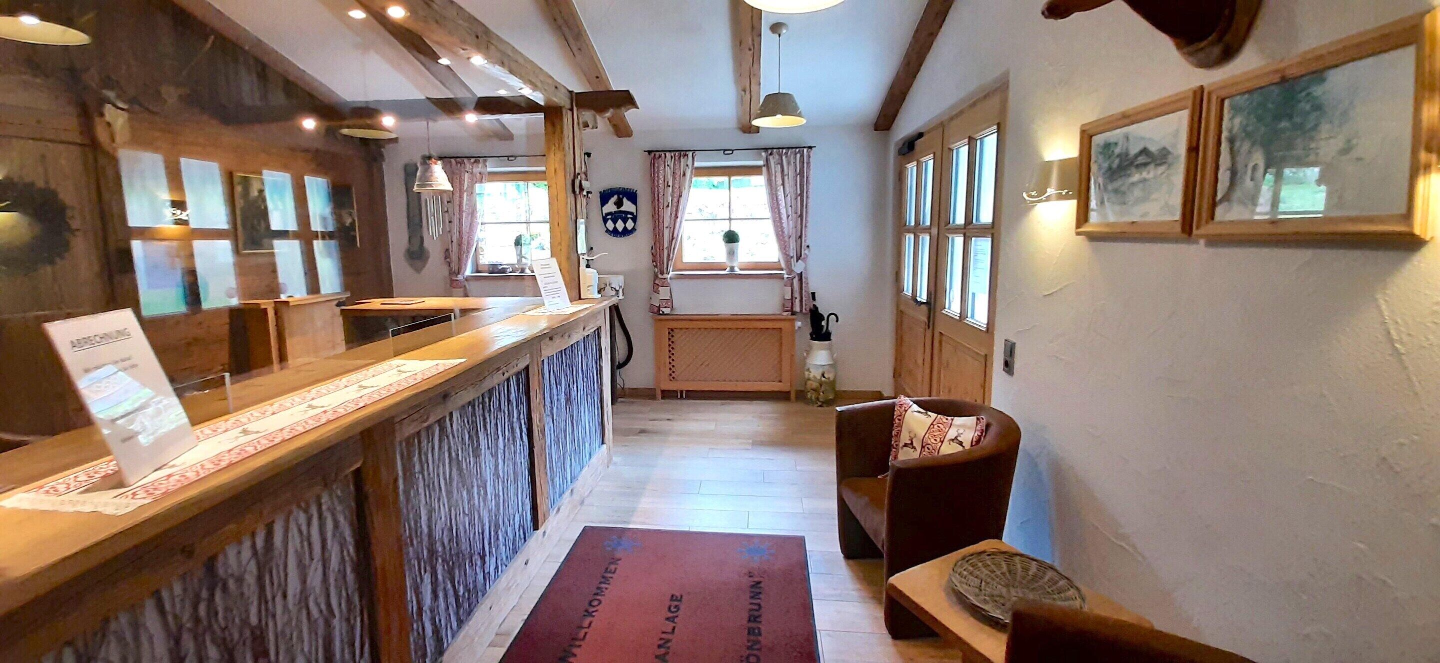 A reception area with a wooden counter, a reception desk, a wooden bench, a cushioned chair, and a door with windows.