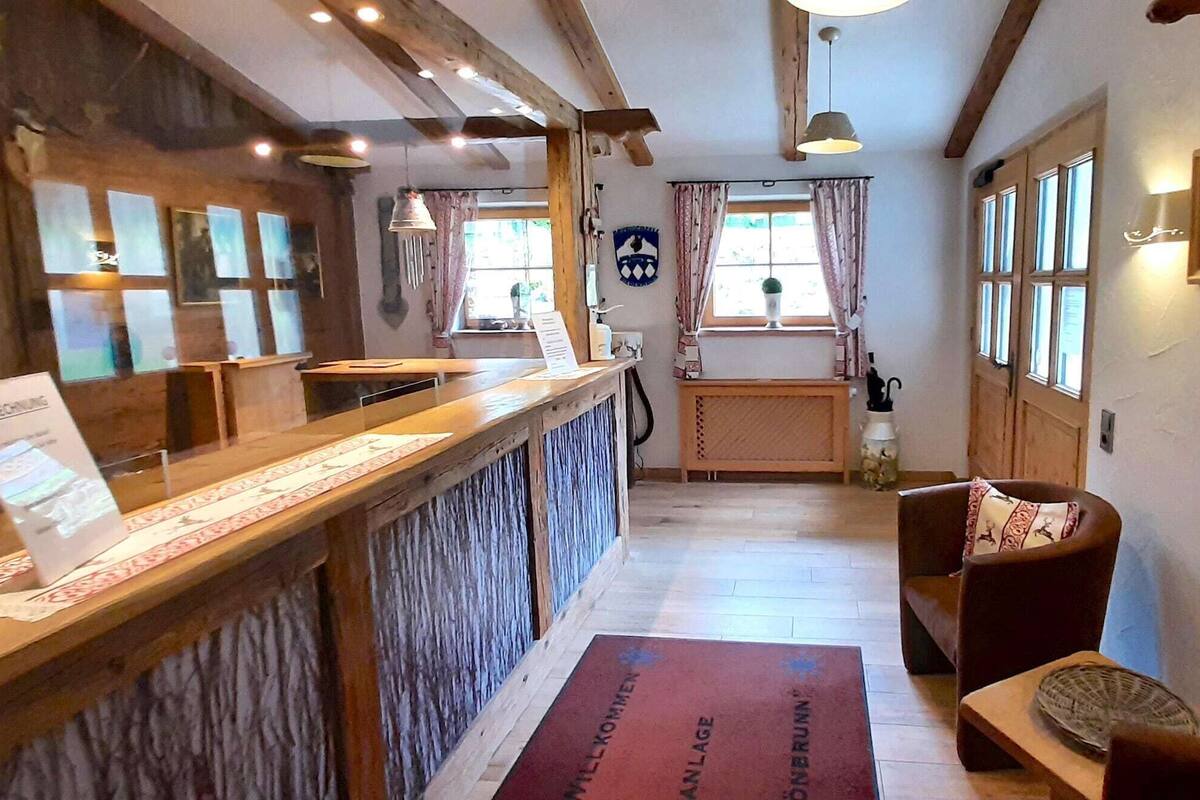 A reception area with a wooden counter, a reception desk, a wooden bench, a rug, and a coat rack.