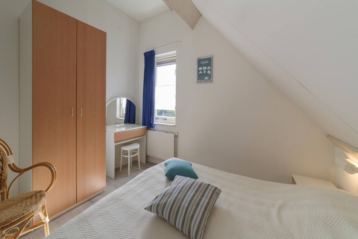 Une chambre à coucher avec un lit, un bureau, une chaise et une armoire.