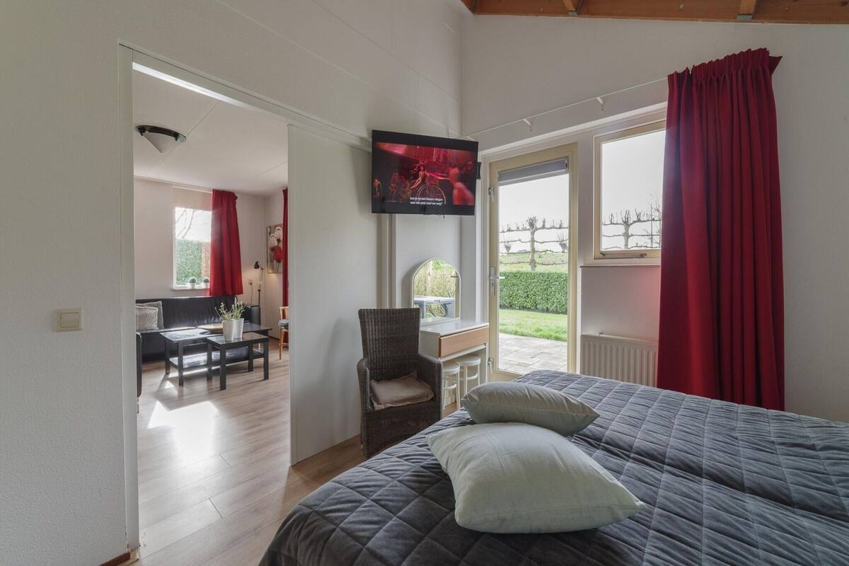 Une chambre à coucher avec un lit, une chaise, un bureau et un téléviseur.