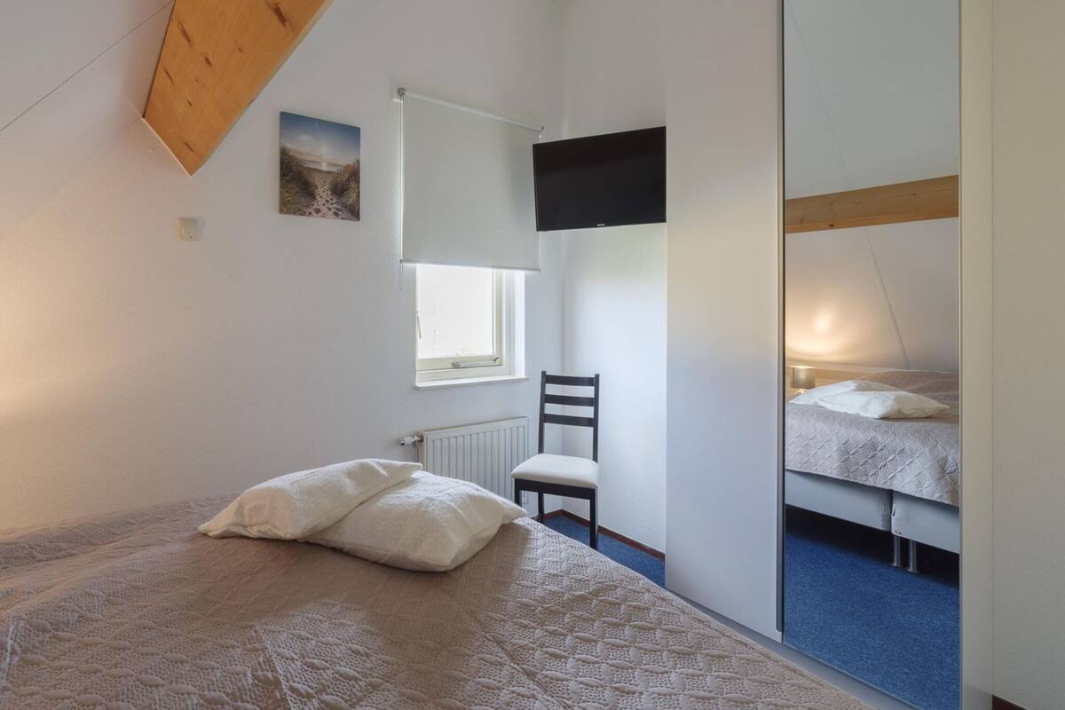 Une chambre avec un lit superposé, un lit simple, une chaise, une fenêtre et un ventilateur de plafond.