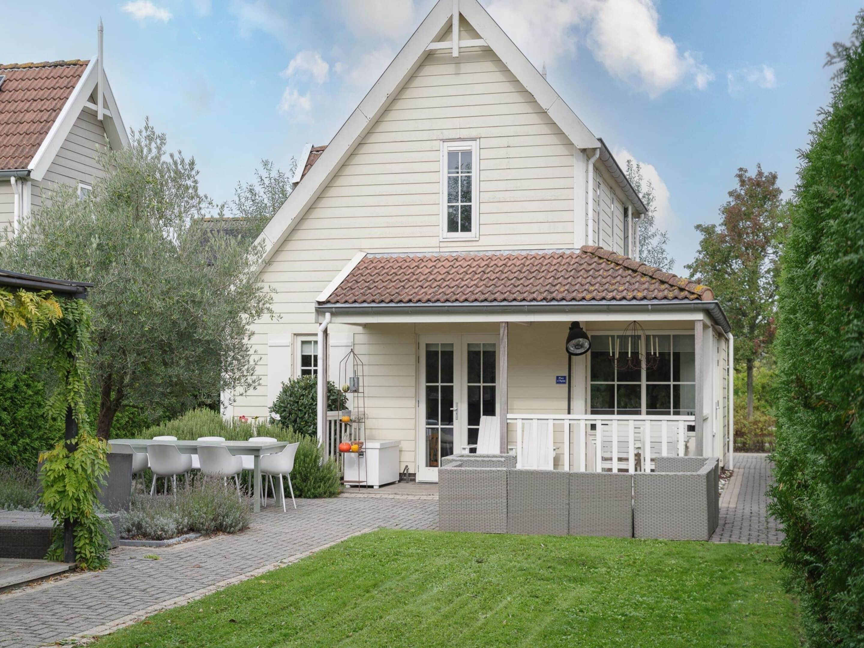 A two-story house with a tiled roof, a front porch, and a fenced backyard.