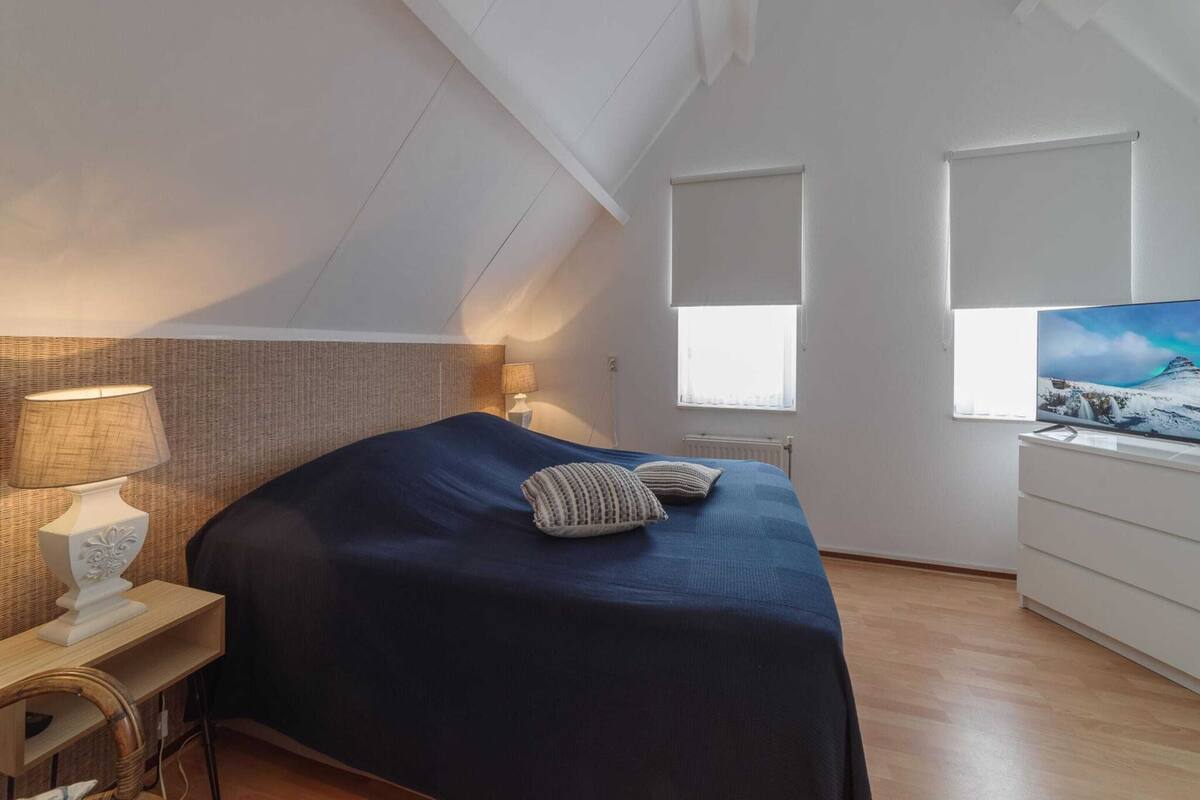 Une chambre à coucher avec un lit, un bureau, une lampe, une commode et un téléviseur.
