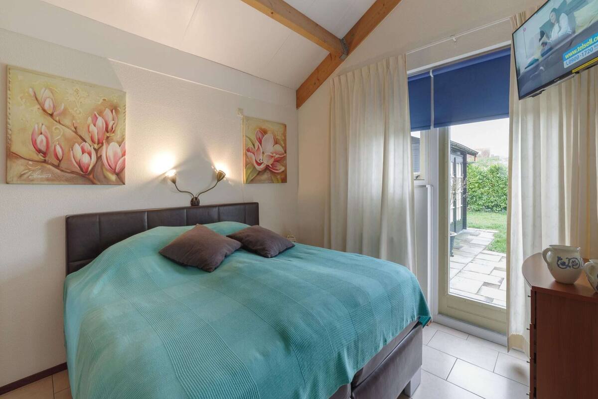 Une chambre à coucher avec un lit, deux lampes fixées au mur et un téléviseur posé sur un meuble.