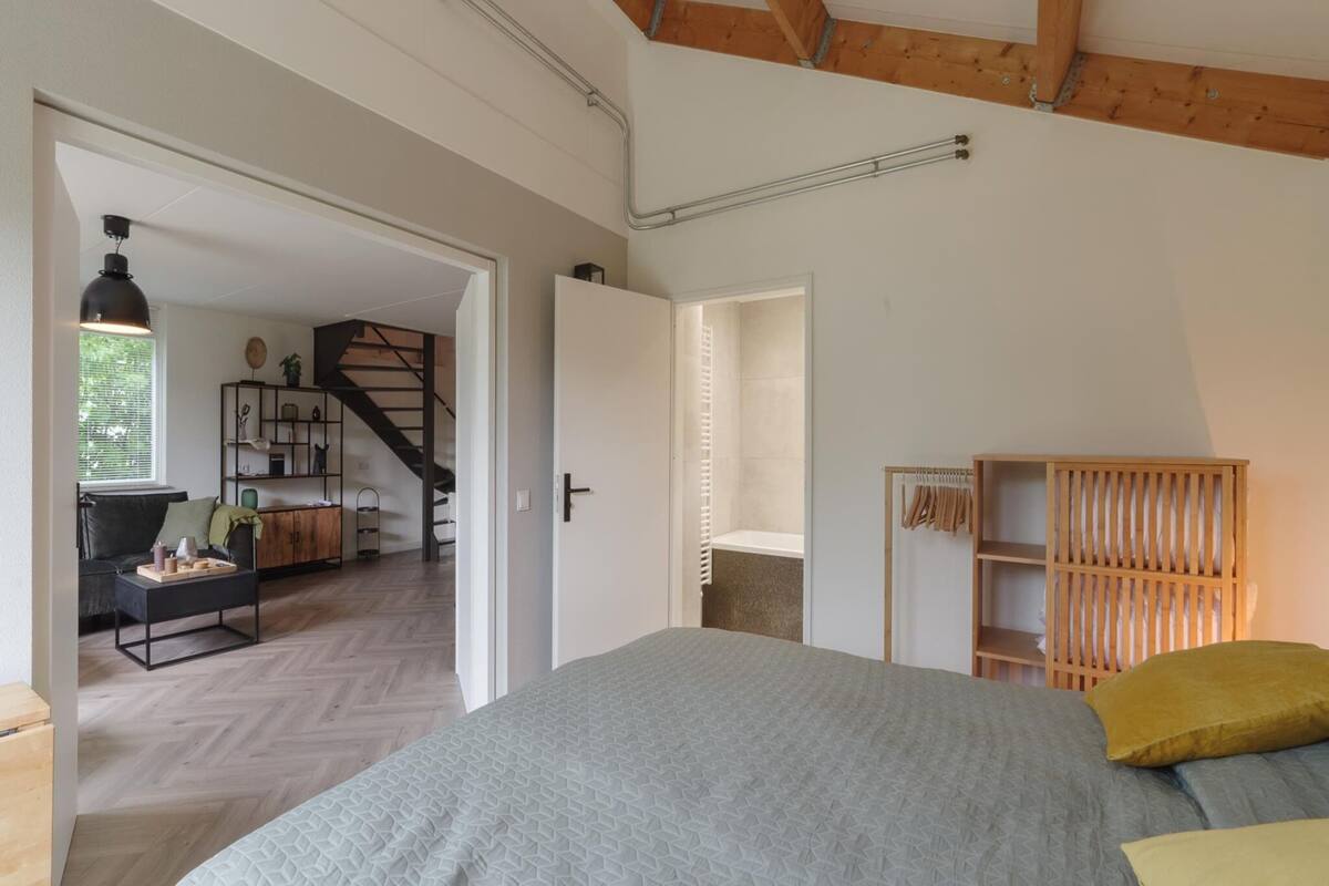 Une chambre à coucher avec un lit, une armoire en bois et un escalier menant à une autre pièce.
