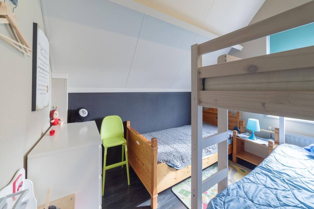 Une chambre avec un lit superposé, un bureau, une chaise et une petite table.