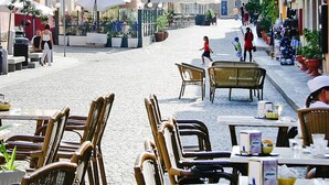 A cobblestone street with outdoor seating and umbrellas, surrounded by buildings with balconies and shops. - Residence I Mirti Bianchi, Santa Teresa Gallura (Santa Teresa di Gallura)