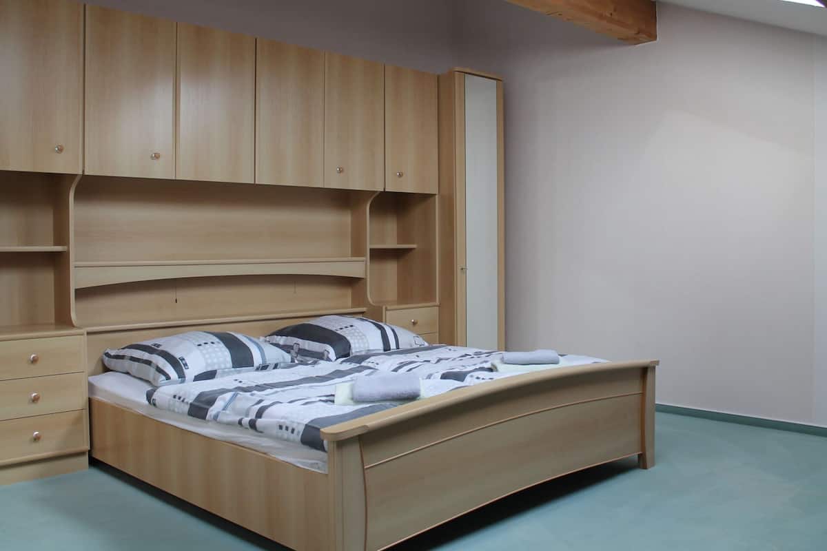 A bedroom with a wooden bed, built-in storage, and a simple design.