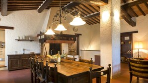 A rustic dining area with a wooden table and chairs, a chandelier, and a stone wall. - Flat With Shared Pool and air Conditioning (Castelfiorentino)