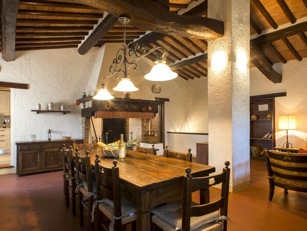 A rustic dining area with a wooden table and chairs, a chandelier, and a stone wall. - Flat With Shared Pool and air Conditioning (Castelfiorentino)