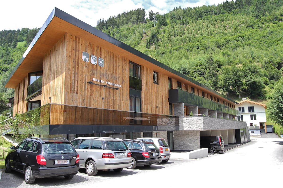A modern building with a wooden facade and a sign reading "Neukirchen Wildkogelbahnen".