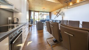 A modern kitchen with a stove, kettle, and dining area with chairs. - Modern Apartment With Balcony and Access to Sauna (Neukirchen am Grossvenediger)