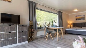 A modern room with a bed, a TV, a dining area, and a wall-mounted wine rack. - Comfortable Holiday Apartment in St. Peter Ording (St. Peter-Ording)