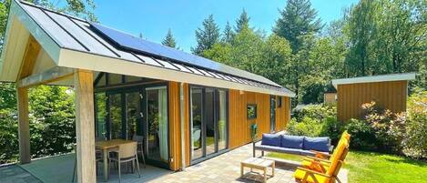 A modern house with a covered patio, a dining area, and a garden.