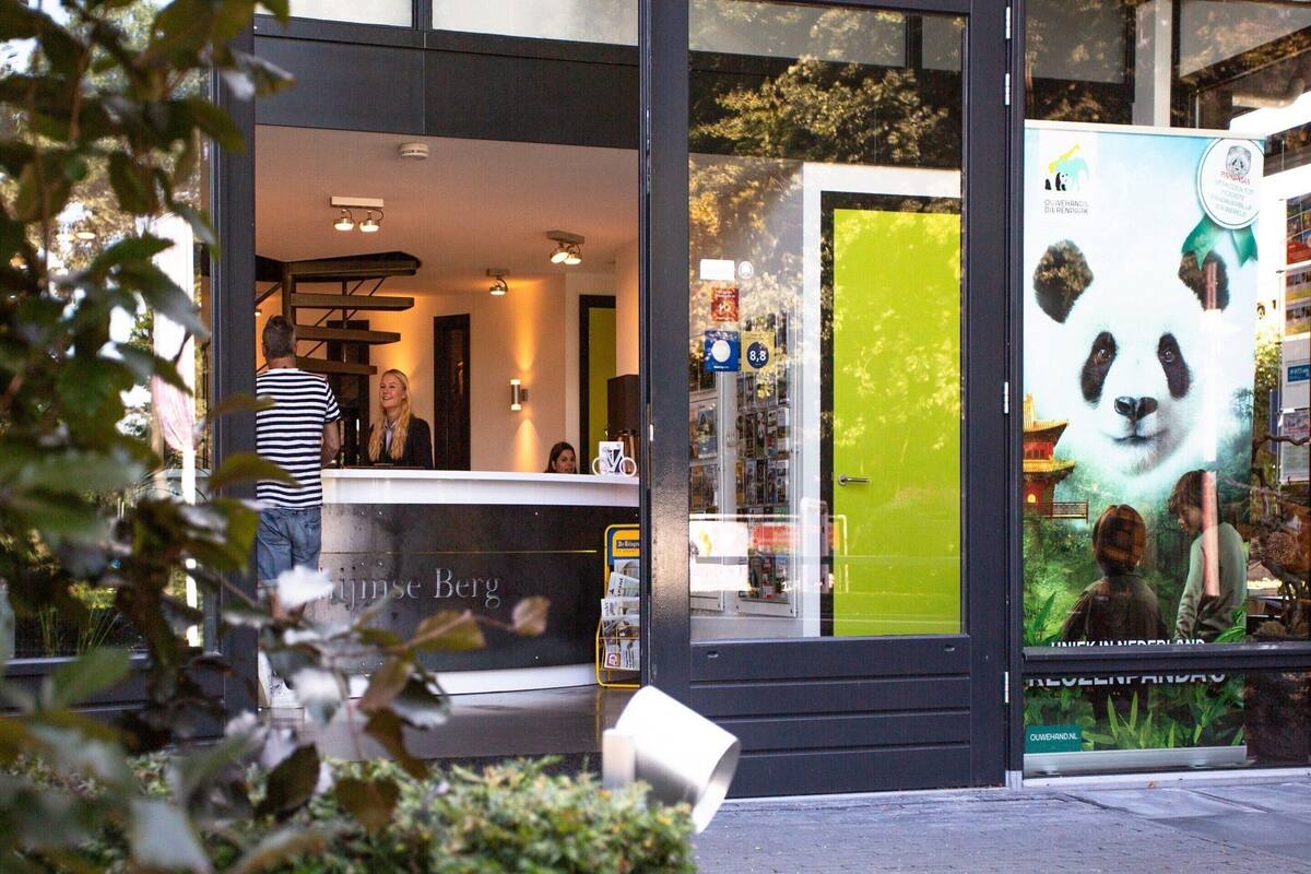 Un bâtiment moderne avec un comptoir d’accueil, une porte verte et une affiche représentant un panda.
