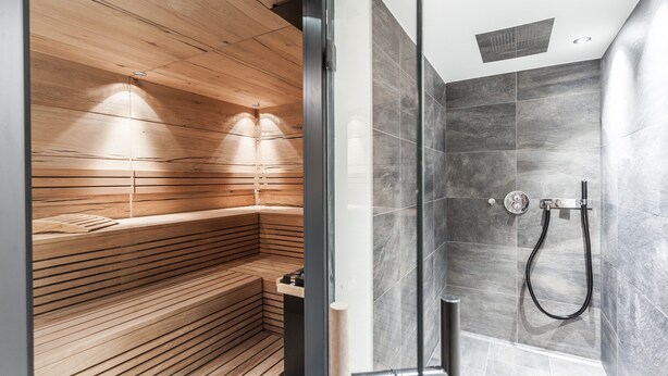 A modern bathroom with a wooden sauna bench and a shower area with grey tiles. - Graceful Chalet in Gaschurn With Sauna (Gaschurn)