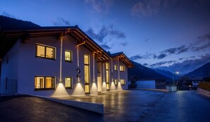 A modern two-story building with multiple illuminated windows and a well-lit entrance. - Graceful Chalet in Gaschurn With Sauna (Gaschurn)
