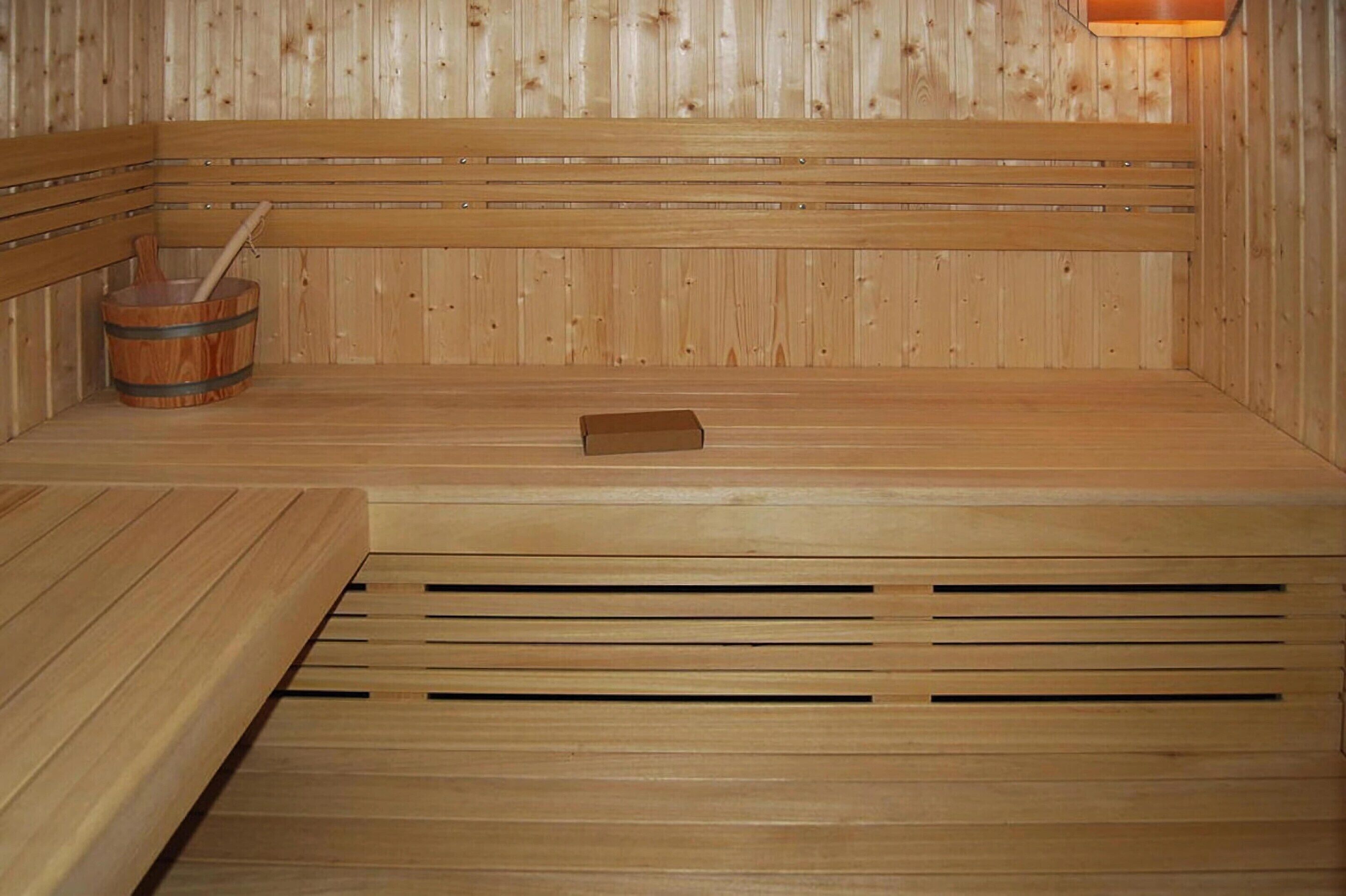 Eine Holzsauna mit Bänken und einem Holzeimer.