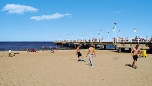 Una playa con gente, un muelle y cielo despejado.