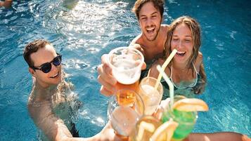 A group of people in a swimming pool holding drinks.