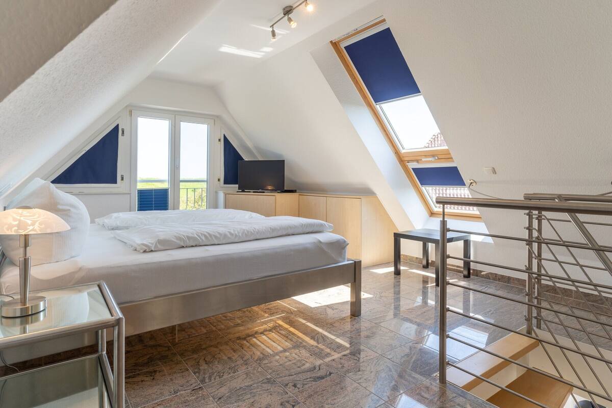 Une chambre à coucher avec un lit, un bureau, une télévision et une lucarne.