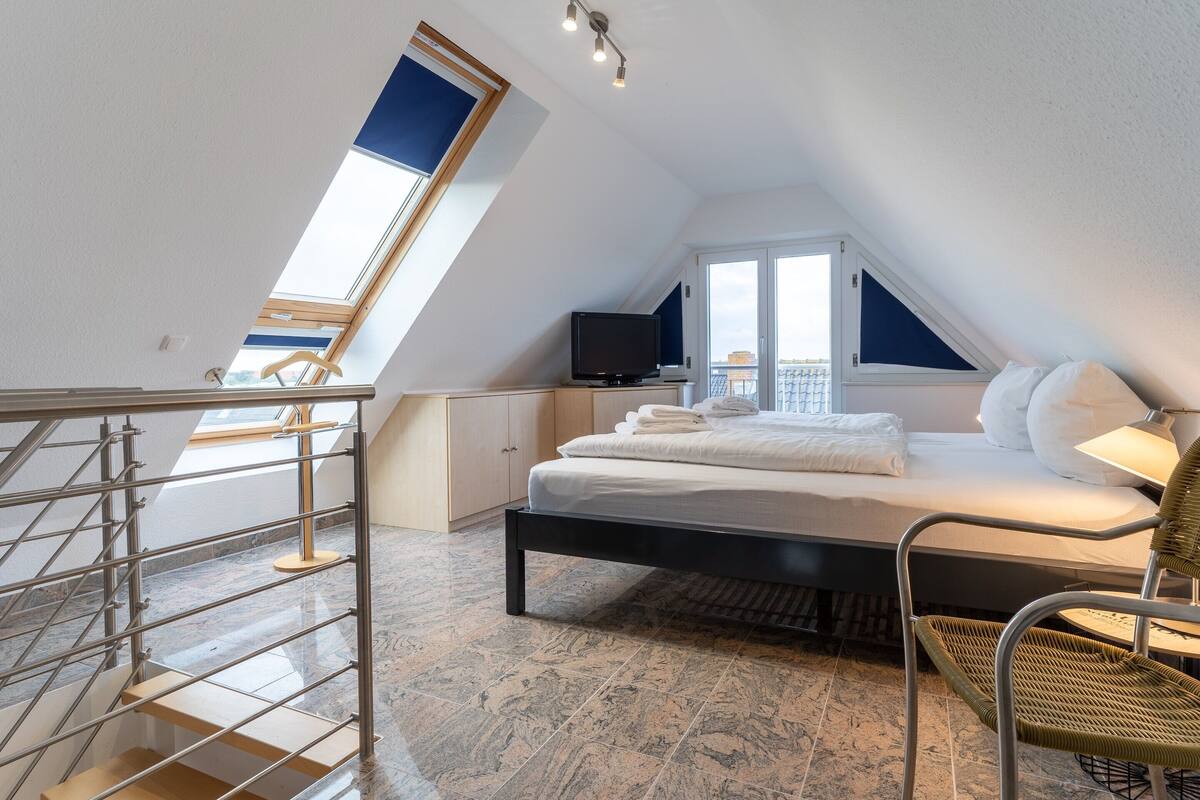Une chambre à coucher avec un lit, une télévision, une chaise et une fenêtre.