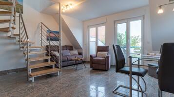 Una sala de estar moderna con una escalera, un sofá, una silla y un comedor.