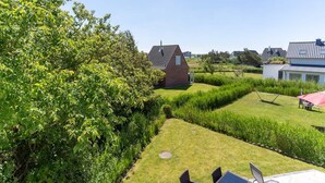A residential area with a well-maintained lawn, a small brick building, and a modern house in the background. - Comfortable Holiday Apartment in St. Peter Ording (St. Peter-Ording)