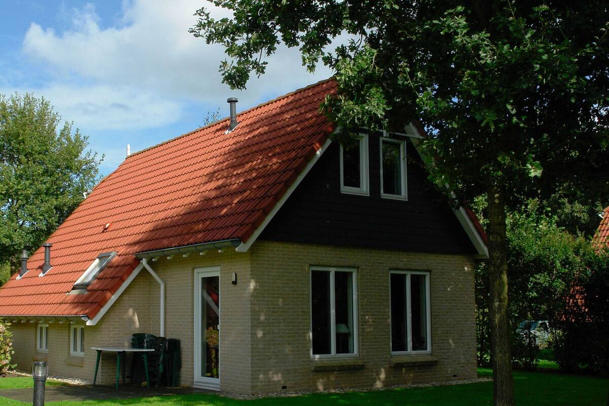 A two-story house with a red-tiled roof, a brick exterior, and a small front porch.