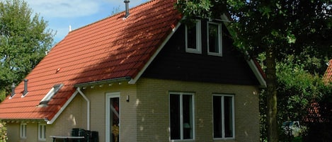 A two-story house with a red-tiled roof, a brick exterior, and a small front porch.
