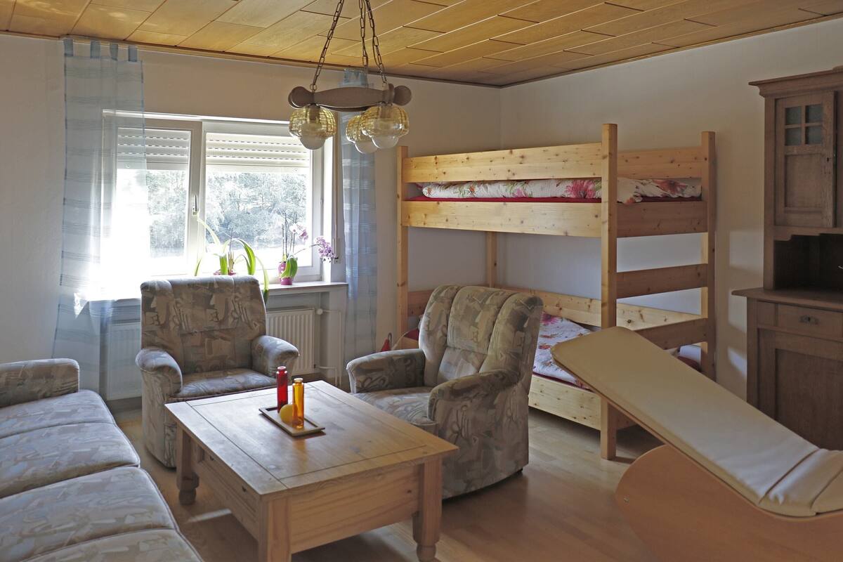 Ein gemütliches Zimmer mit einem Etagenbett, einem Holztisch mit Kerze und zwei Sesseln.