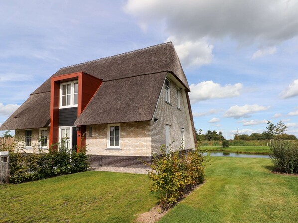 Une maison avec un toit à forte pente, une façade en briques et une pelouse bien entretenue.