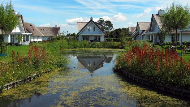 A traditional European-style building with a central courtyard, surrounded by lush greenery and a small pond. - Beautiful Villa With Lots of Comfort, Near North Sea Beach (Noordwijk)