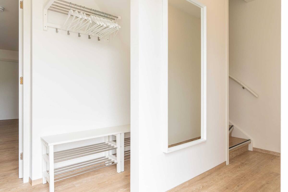 A white hallway with a bench and a coat rack.