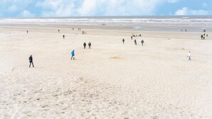 A wide sandy beach with people walking and playing, and the ocean in the background. - Lovely Apartment on Ameland Near Nes (Nes)