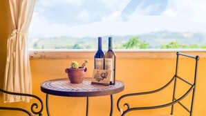 Ein Balkon mit zwei Weinflaschen, einem Blumentopf und einer Speisekarte auf einem runden Tisch.