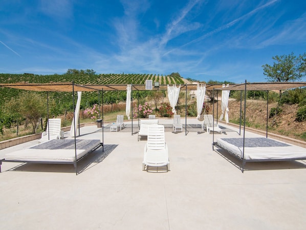 An outdoor seating area with white lounge chairs and a pergola structure. - Charming Apartment in Ascoli Piceno Near Village (Ripatransone)