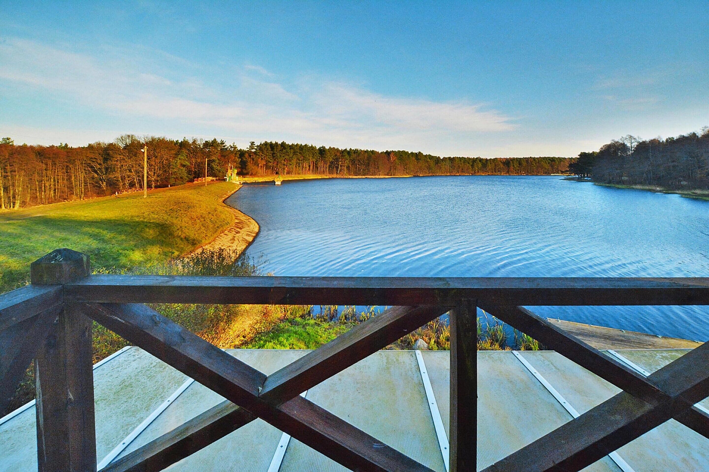 A wooden deck overlooking a calm lake with a forested shoreline.
