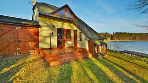 A house with a porch, a garage, and a view of a lake. - Holiday House by the Lake With a Fireplace (gmina Manowo)