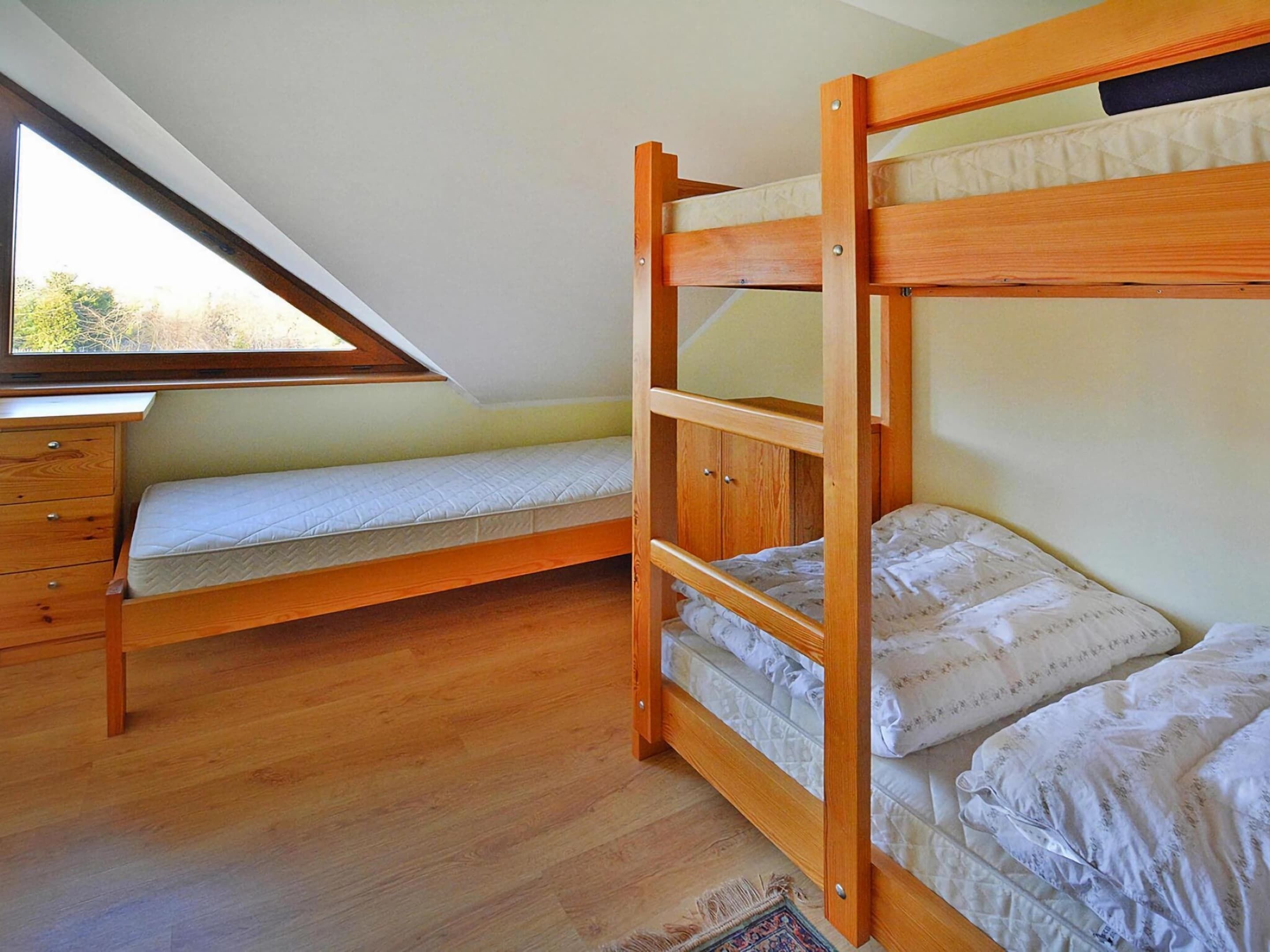 A dorm-style room with a bunk bed, a desk, and a window.