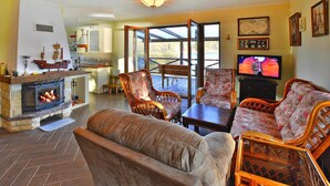 A living room with a fireplace, comfortable seating, a television, and a view of the outdoors. - Holiday House by the Lake With a Fireplace (gmina Manowo)