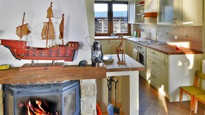 A cozy kitchen with a wood-burning stove, a ship model, and a view through the window. - Holiday House by the Lake With a Fireplace (gmina Manowo)
