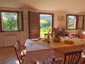 A dining area with a table set for four, a vase of flowers, and a bottle of wine. - Property With Swimming Pool, Spacious Garden, Private Terrace and Views (Apecchio)